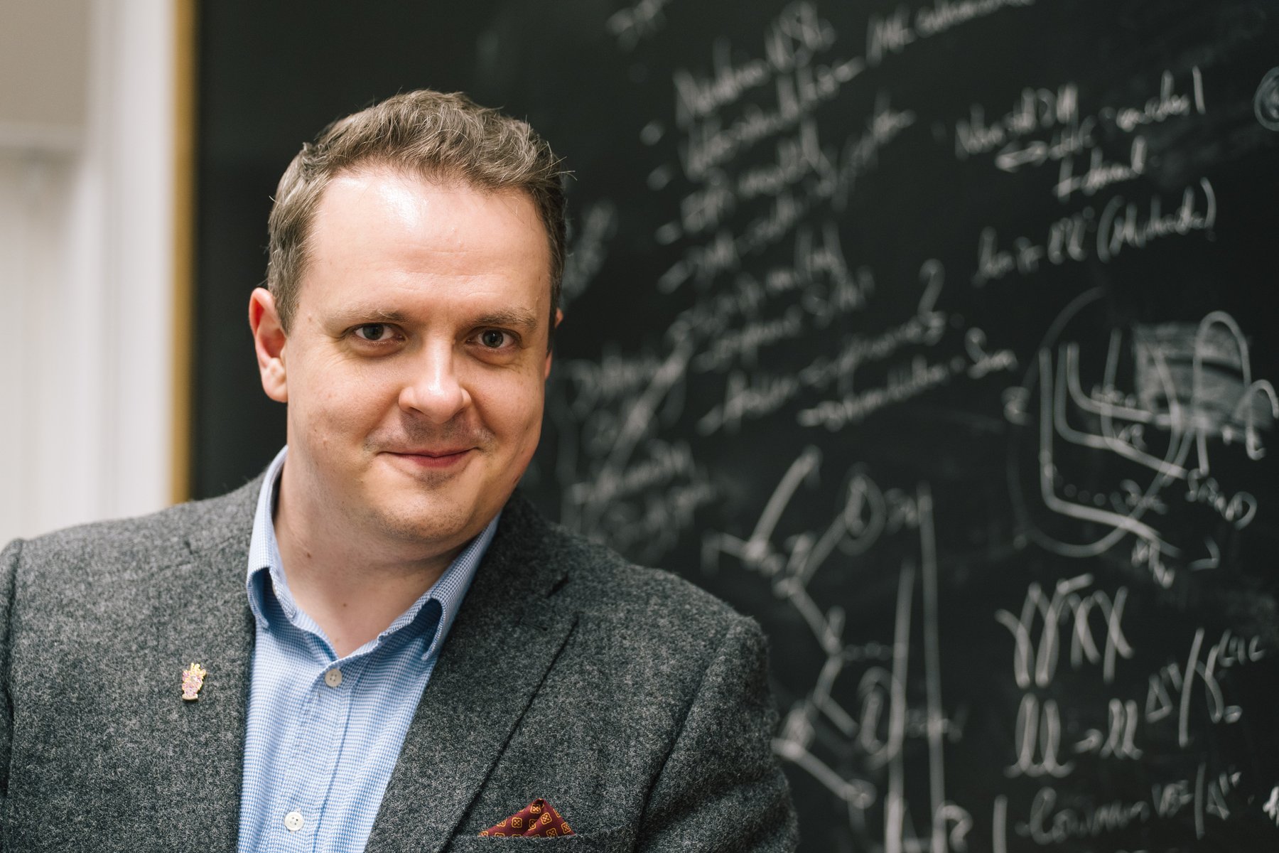 Darren Price at a blackboard covered in particle-physics equations